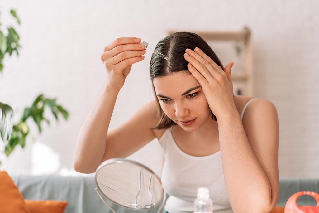 woman putting hair oil on her scalp