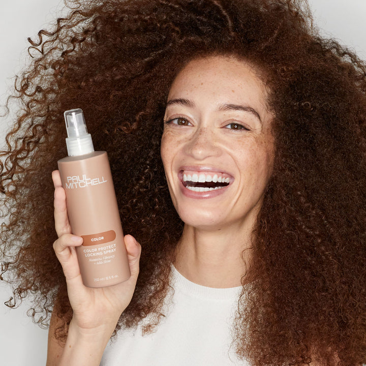 Paul Mitchell Color Protect Locking Spray - model holding the bottle